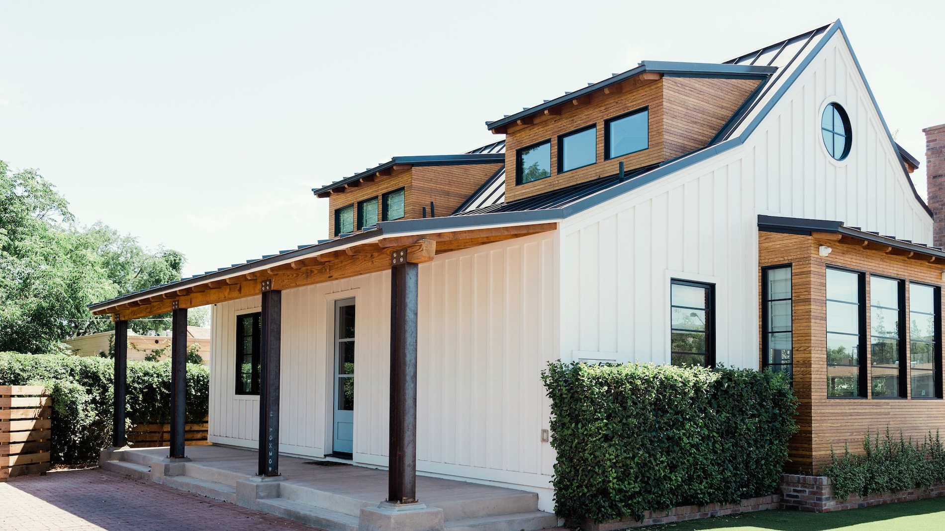 White board-and-batten home with wood-clad dormers and a covered porch, showing a home addition in Lakewood and Cerritos